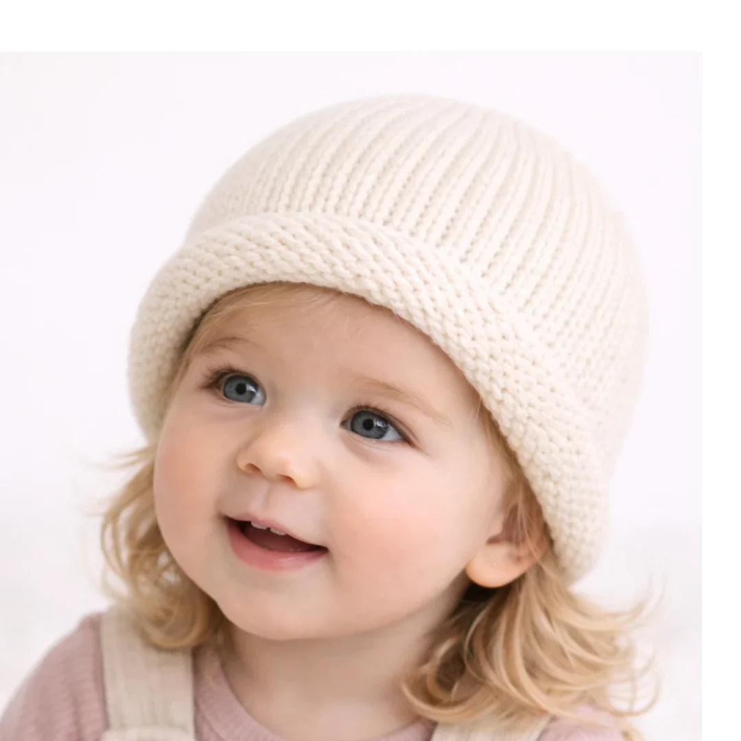Baby wearing cozy cream knit beanie, soft ribbed texture, perfect for little ones