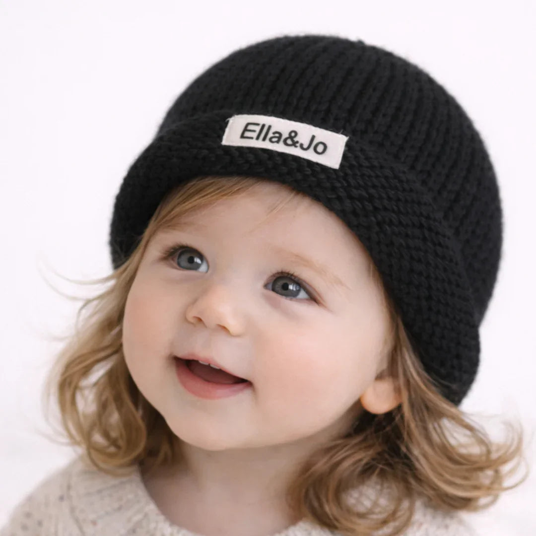Baby wearing black knit beanie with Ella&Jo logo, cozy kids winter hat