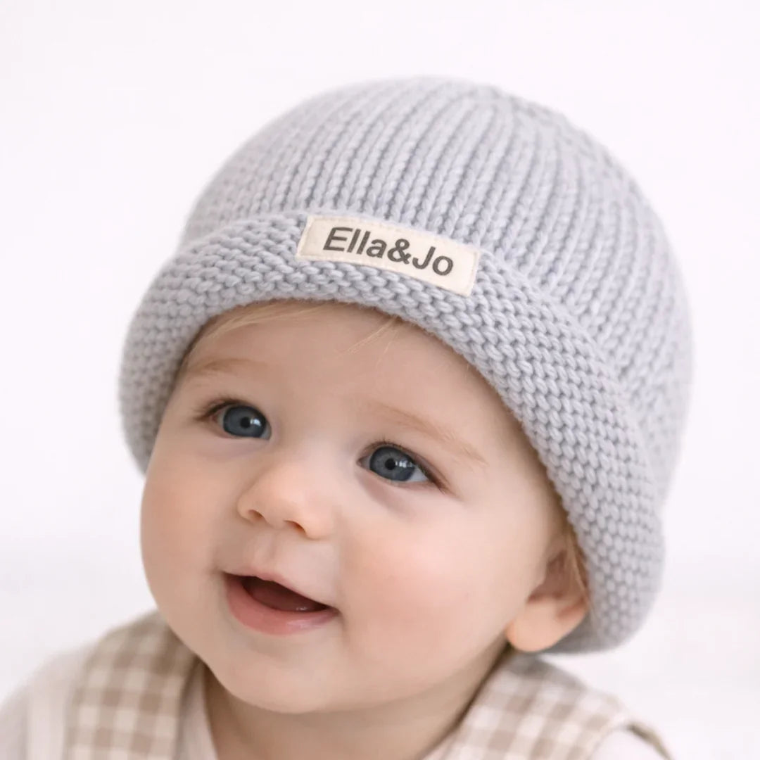 Baby wearing soft gray knit beanie with Ella&Jo label, cozy and stylish for infants